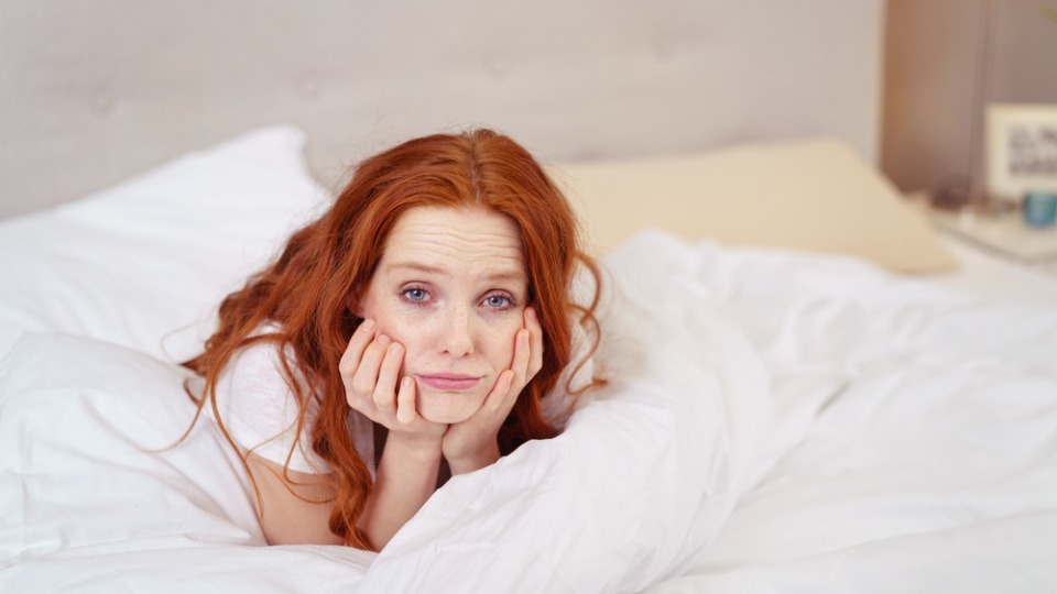 Vitamin-D3-Mangel kann zu Müdigkeit und Abgeschlagenheit führen Eine Frau im Bett kämpft mit Abgeschlagenheit