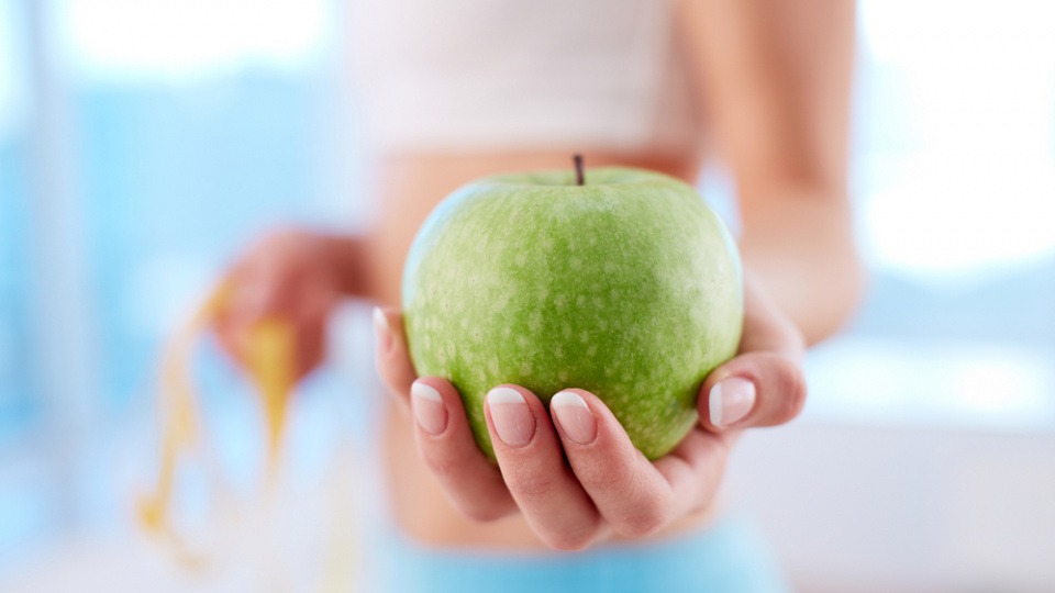 Äpfel gelten als sehr gesund, vertreiben Hunger und helfen beim Abnehmen Eine Frau, die abnehmen möchte, hält einen Apfel