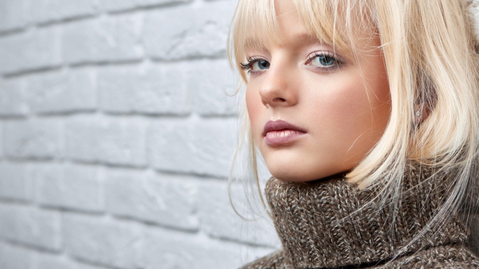 Ausgefranster Pony Eine blonde Frau hat einen ausgefransten Pony