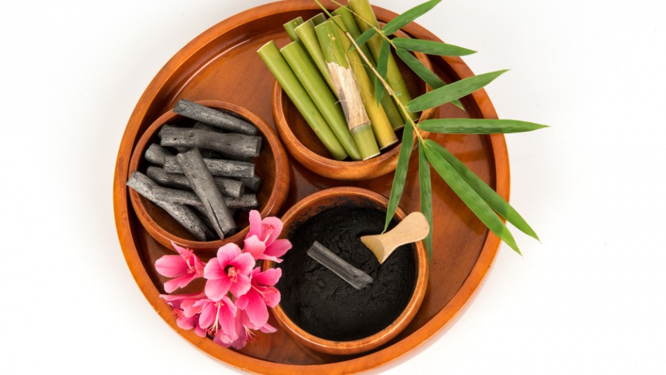 Bambuskohle nimmt überschüssiges Fett der Haut auf Bambus, Kohle und Bambuskohle sind in Schüsseln verteilt