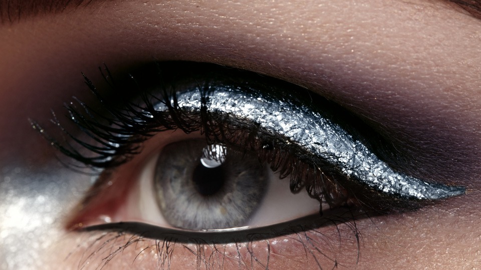 Flüssige Eyeliner in allen möglichen Farben liegen auch 2019 weiterhin im Trend. Eine Frau trägt einen silbernen Eyeliner