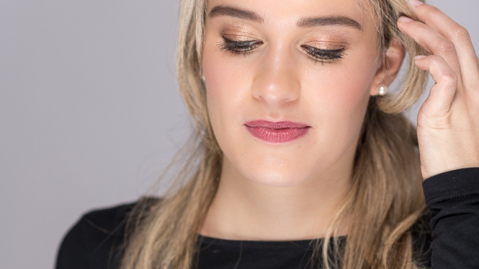 Iris Hagen stimmt ihren Make-up-Workshop in Linz auf deine individuellen Bedürfnisse ab. Eine Frau ist geschminkt und streicht sich Haare aus dem Gesicht