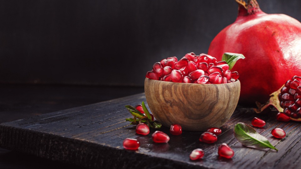 Granatapfel im Ganzen und zerlegt in einer Schüssel Granatapfel im Ganzen und zerlegt in einer Schüssel