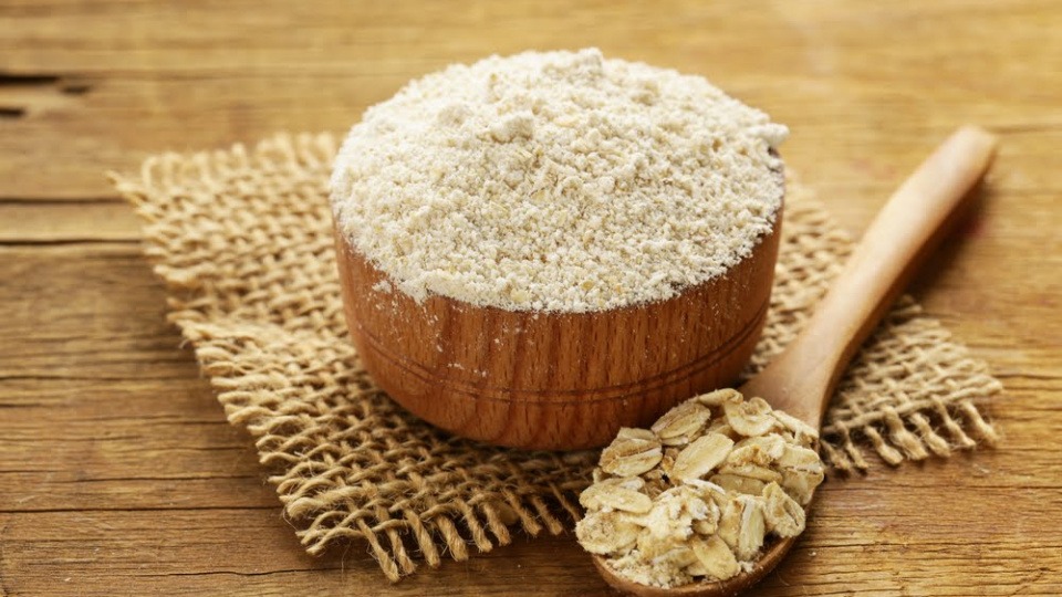 Haferflocken sind reich an Magnesium und daher gut für unsere Muskeln Haferflocken auf einem Löffel neben einer Schüssel