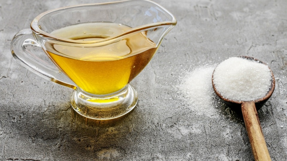 Ein Honig-Zucker-Peeling hilft gegen trockene Lippen Eine Schüssel Honig steht auf einem Tisch neben Zucker