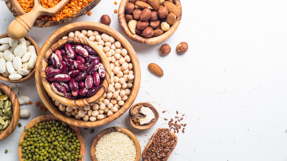 Die Low Carb Ernährungsmethode ersetzt schädlichen, wertlosen Zucker im Alltagsessen einfach durch kohlenhydratarme Lebensmittel Auf einem Tisch sthen verschiedene Hülsenfrüchte in Schüsseln