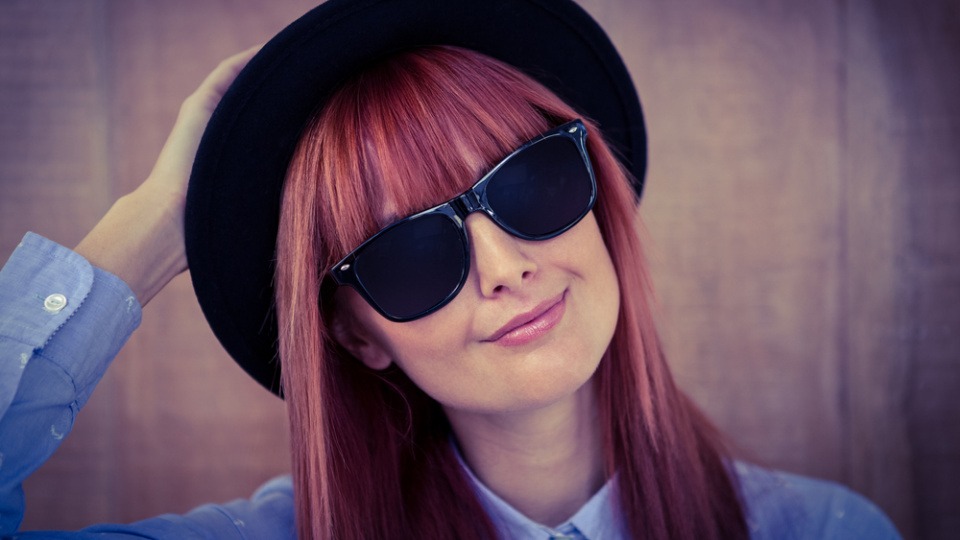 Bei einem eckigen Gesicht passt ein Pony ideal zu dir Eine Frau hat eine Sonnenbrille und einen Pony