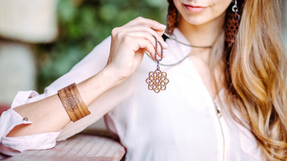 Eine Frau hat eine Kette sowie ein Armband aus Holz Eine Frau hat eine Kette sowie ein Armband aus Holz