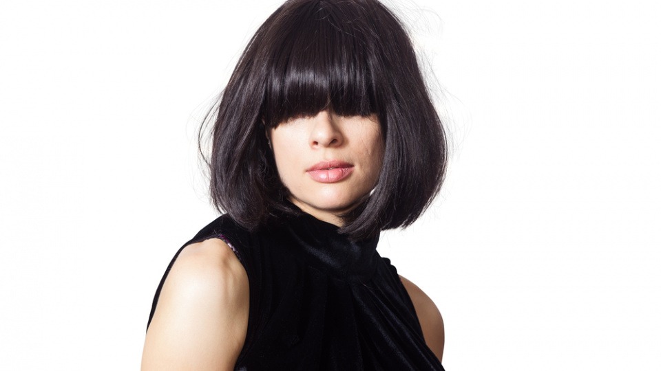 Bei herzförmigem Gesicht steht dir ein langer Pony ausgezeichnet Eine Frau hat einen langen Pony, der ihre Augen verdeckt