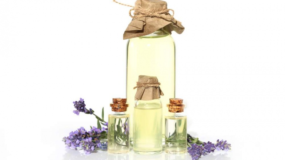 Die Anwendungsgebiete von Lavendelöl sind weitreichend Fläschchen sind gefüllt mit Lavendelöl, daneben liegt Lavendel