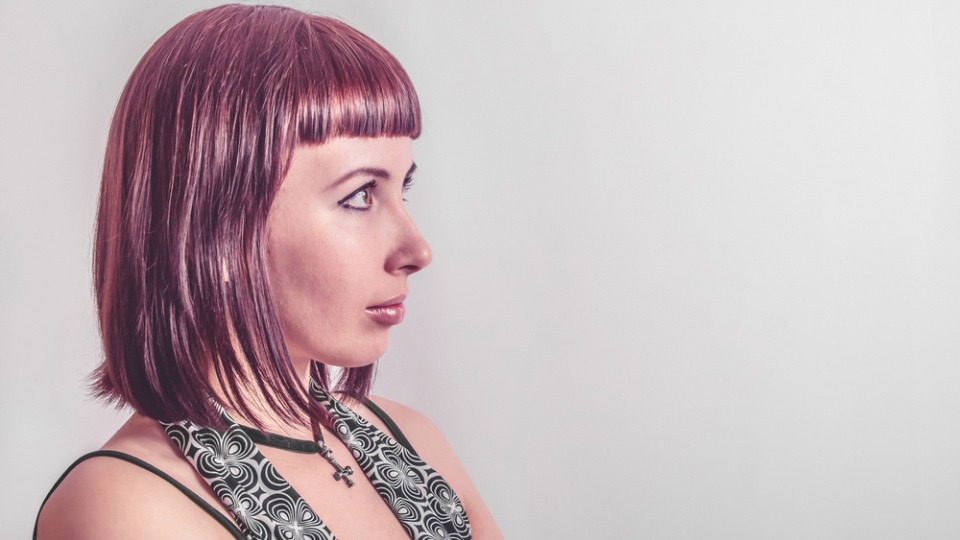 Ein extrem kurzer Pony lässt dich strenger wirken Eine Frau hat lila Haare und eine Ponyfrisur