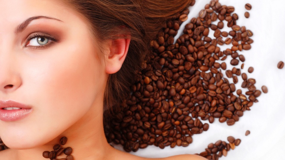 Kaffee ist eine Möglichkeit, die Haare natürlich zu färben Frau liegt mit ihren Haaren auf Kaffeebohnen