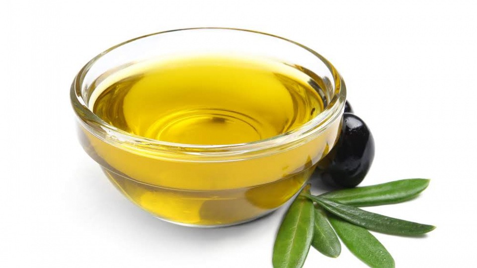 Bei trockenen Schuppen hilft es Olivenöl und Honig zu mischen Eine Schale mit Olivenöl und Olive