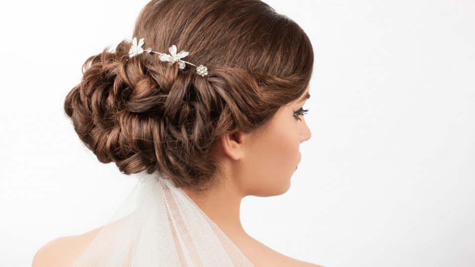 Besonders wichtig ist, dass der Schleier gut befestigt wird Eine Frau mit einem Schleier unter der Brautfrisur