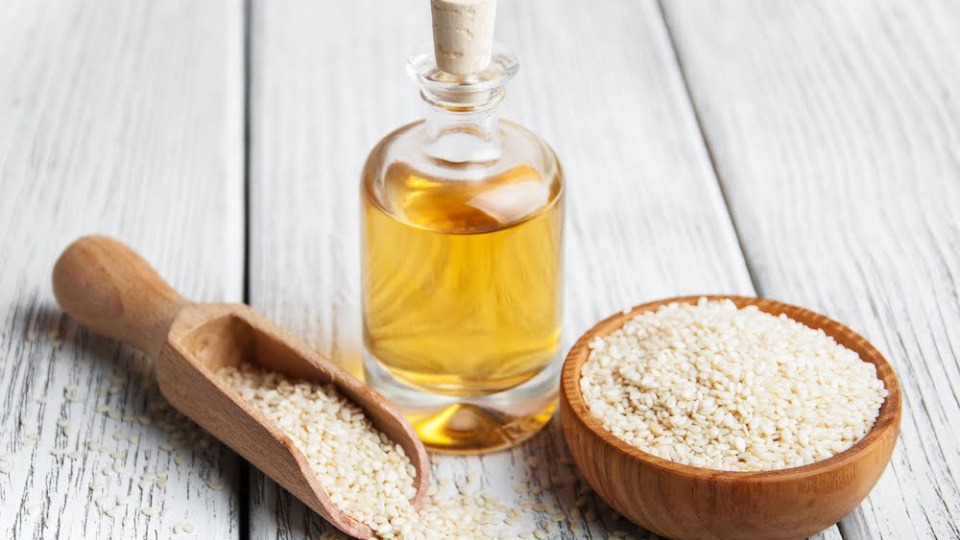 Neben Kokosöl hilft auch Sesamöl bei Schuppen Sesam und Sesamöl stehen auf einem Tisch
