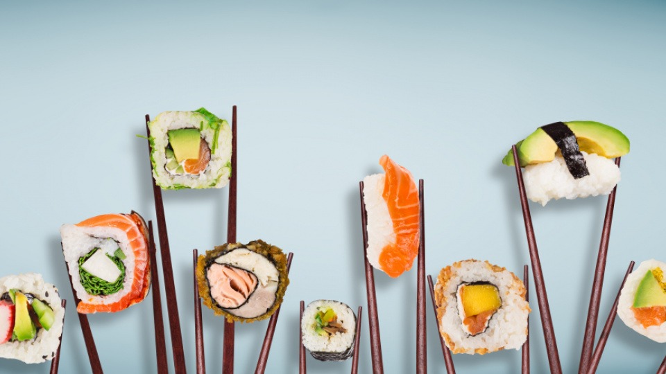 Auch Sushi ist eine schmackhafte Möglichkeit, Reis zu essen Verschiedene Sushi mit Reis werden mit Stäbchen gehalten