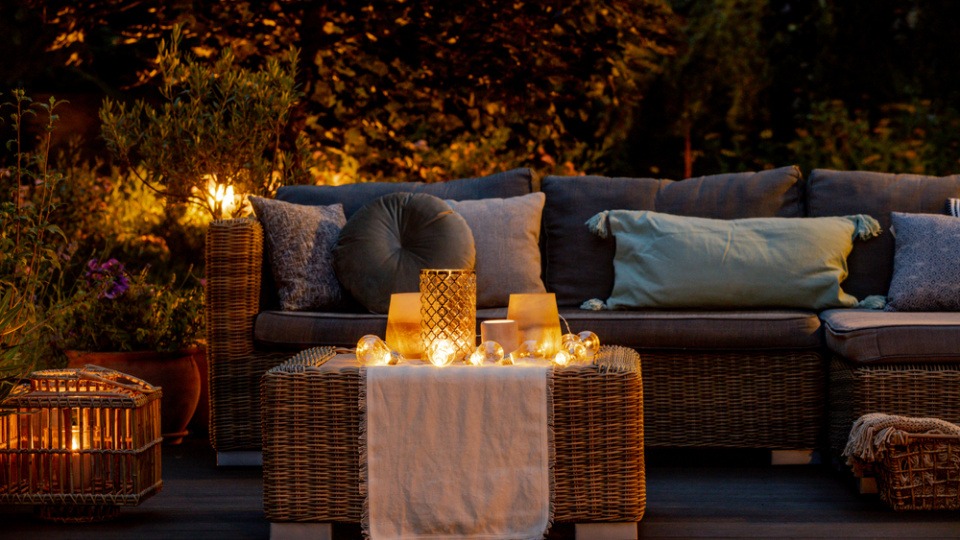 Auch kleine Terrassen können durch Lichter etwas Besonderes werden und zum Wohlfühlen einladen Idee Terrasse gestalten mit Kerzen auf einem Tisch vor einem Sofa auf einer Terrasse