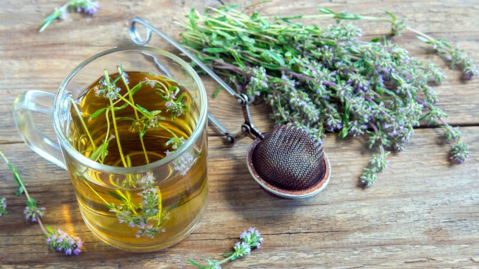 Thymian ist ein beliebtes Hausmittel bei Husten, Halsschmerzen und Heiserkeit Thymian liegt neben einer Tasse Thymiantee