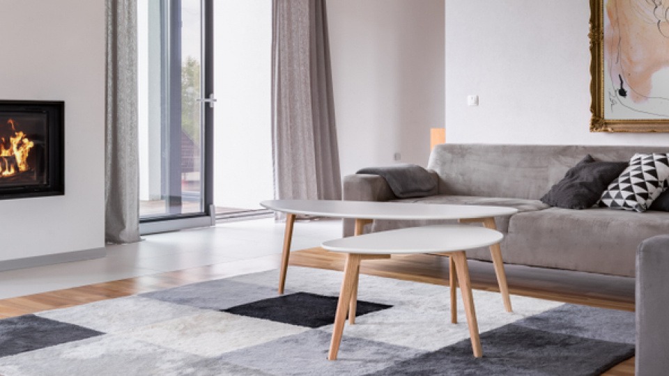 Lichtinseln mit mehreren Lichtquellen sind das Geheimnis, wenn es um Gemütlichkeit geht. Ein graues Wohnzimmer mit Kamin.