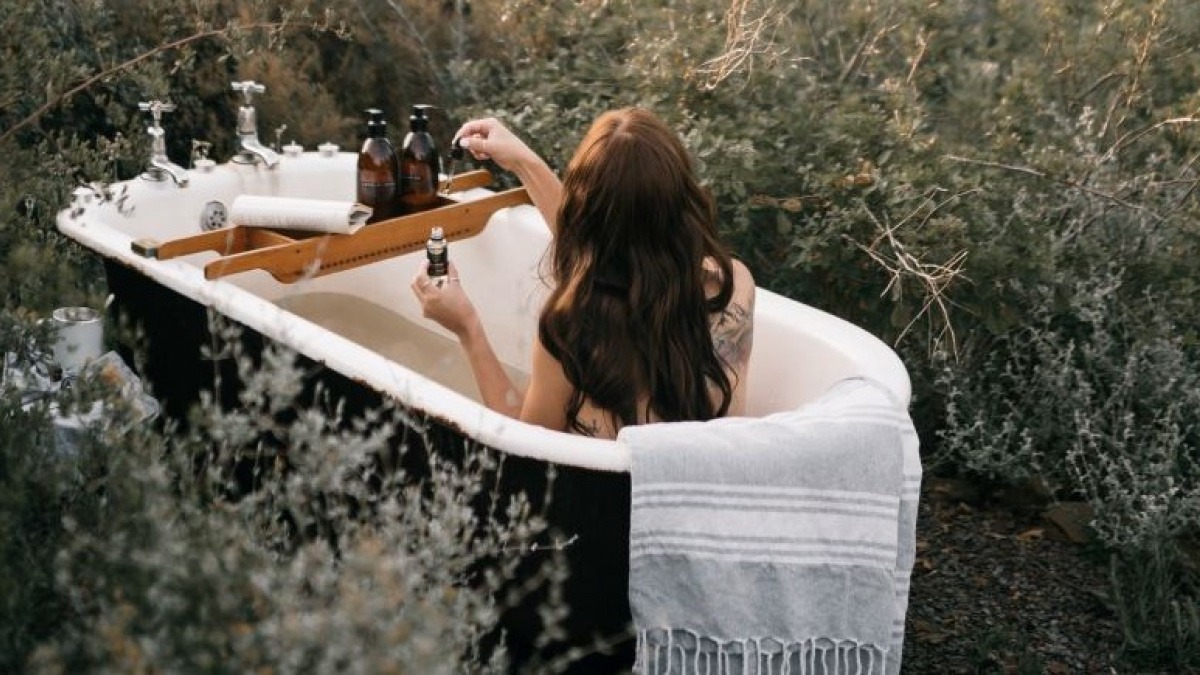 Frau badet zwischen Kräutern in einer Badewanne