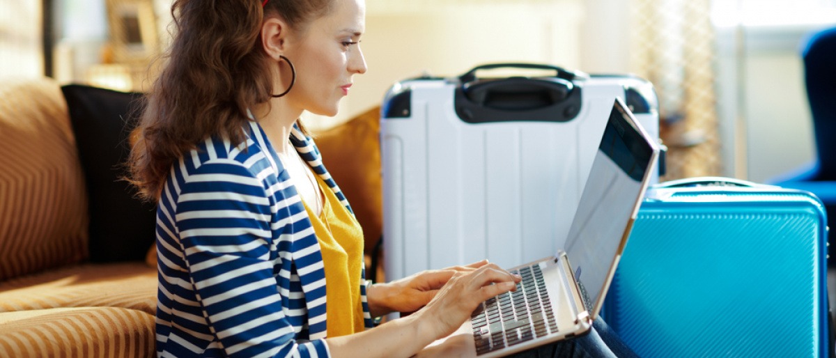 Am Boden zwischen Reisekoffern sitzende Frau arbeitet am Notebook