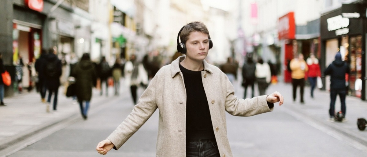 Junger Mann mit Kopfhörern tanzt in Freiheit auf der Straße einer Stadt