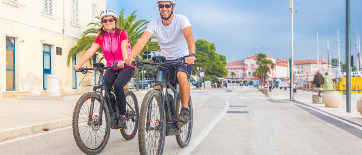 Zwei Urlauber sind auf einem E-Bike unterwegs
