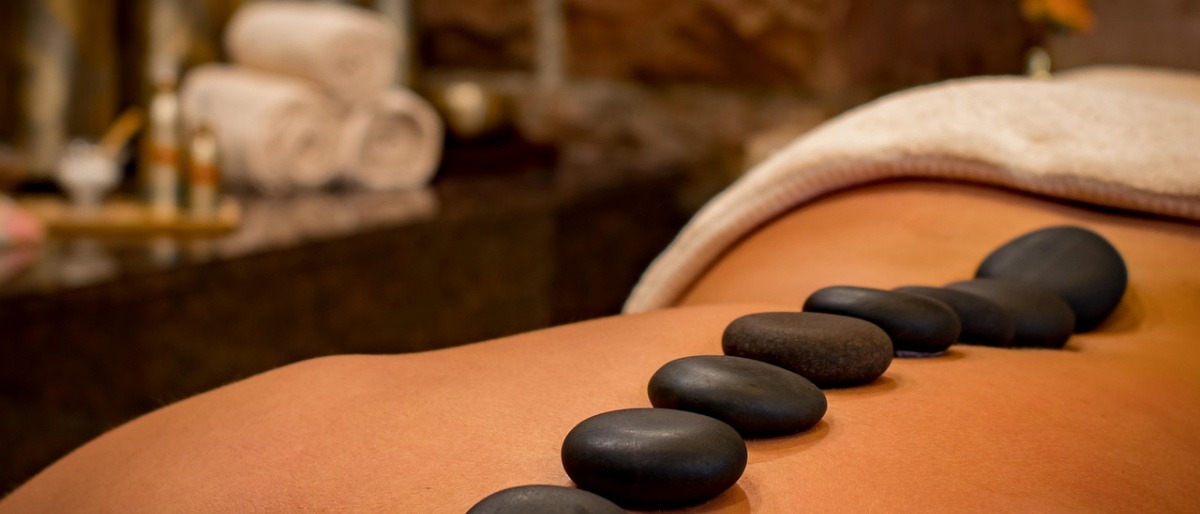 Auf einem Rücken liegen Steine für eine Hot Stone Massage