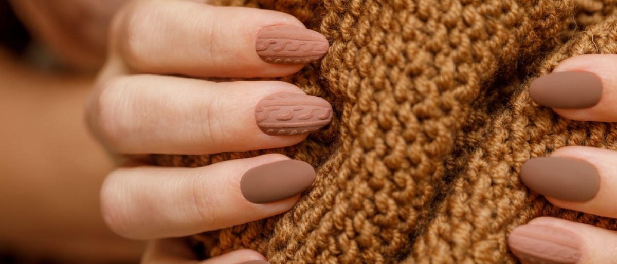 Finger mit Nagellack in Nagellack-Trend braun