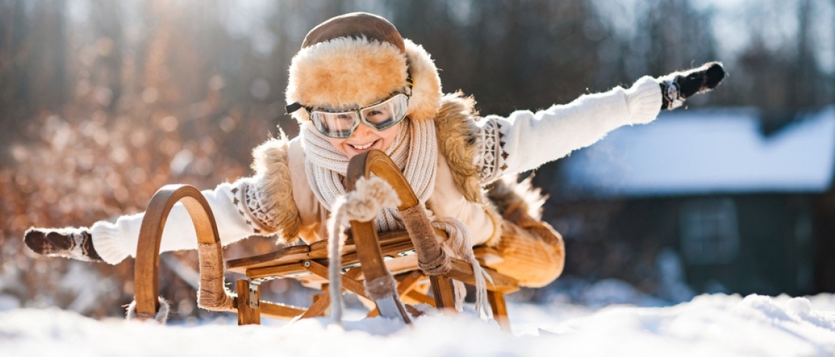 Person auf einer Rodel gegen Winterblues