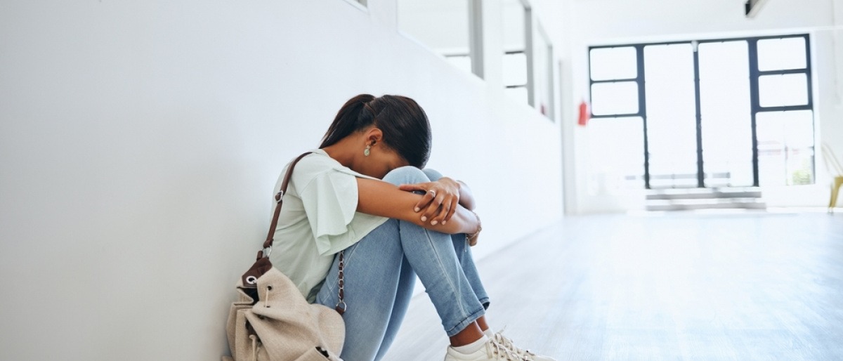 Mädchen sitzt wegen Prüfungsangst verzweifelt am Boden einer Schule