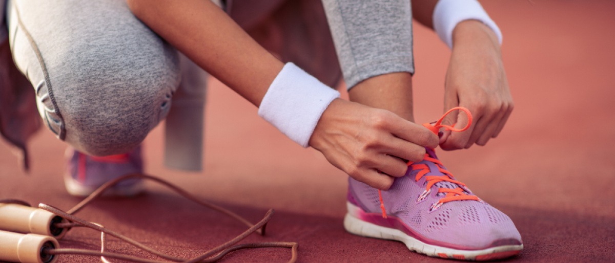 Eine Frau schnürt ihre Sportschuhe, um sportlicher zu werden