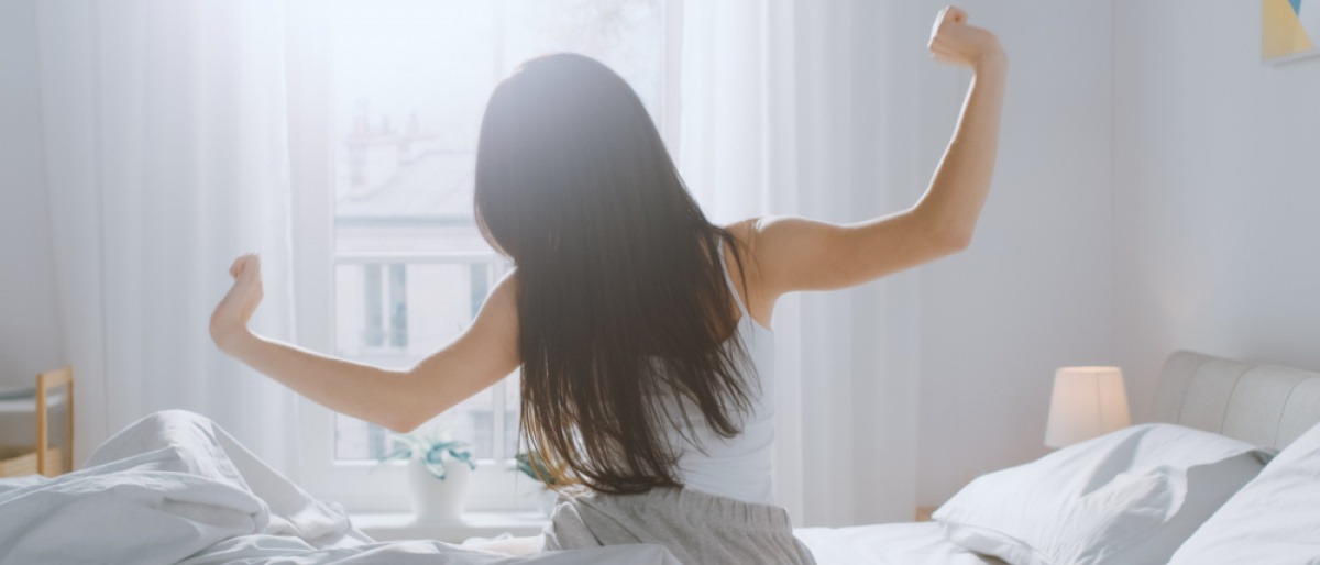 Frau streckt sich im Bett für einen guten Morgen