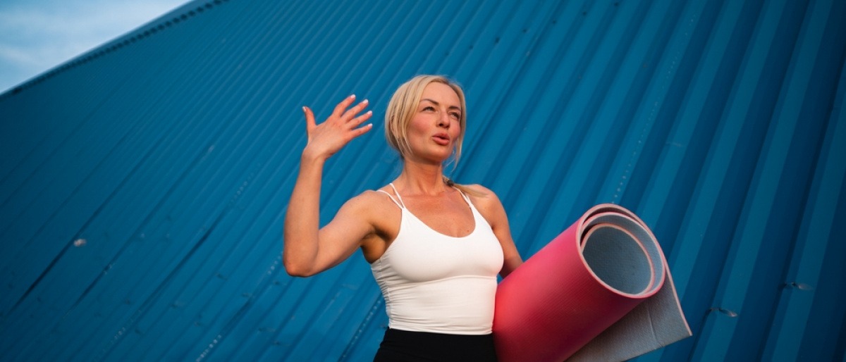 Frau läuft mit Yogamatte über Dach.