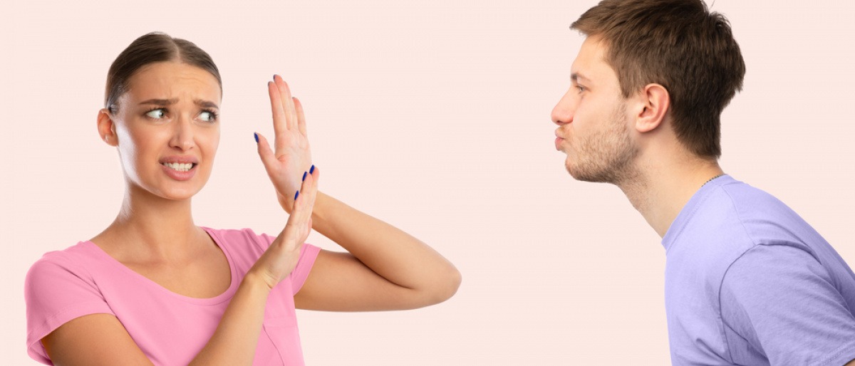 Ein Mann will eine Frau küssen, die ihm ihre Abneigung offen demonstriert