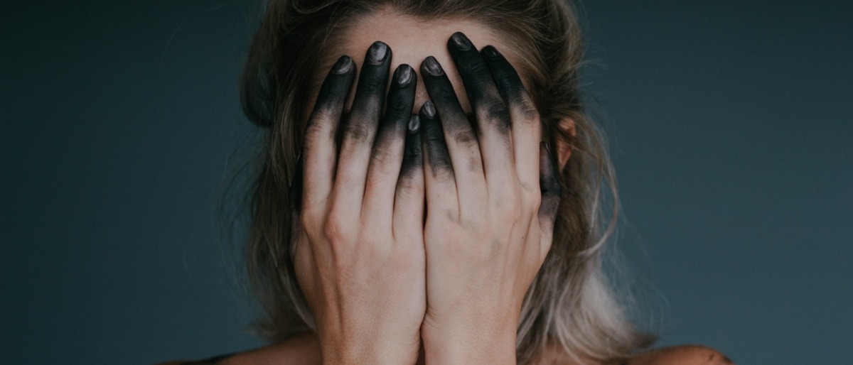 Eine Frau hält sich mit Aktivkohle auf den Händen das Gesicht zu