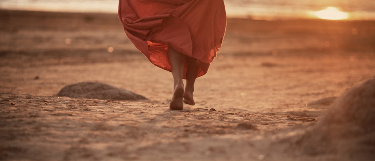 Eine Frau geht alleine am Strand