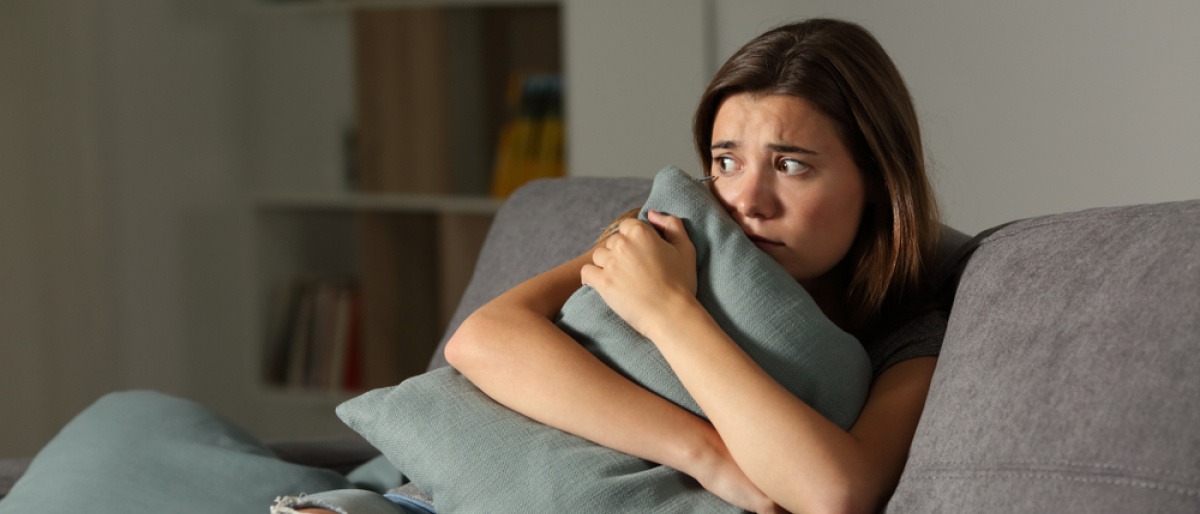 Eine Frau sitzt zuhause und hat Angst