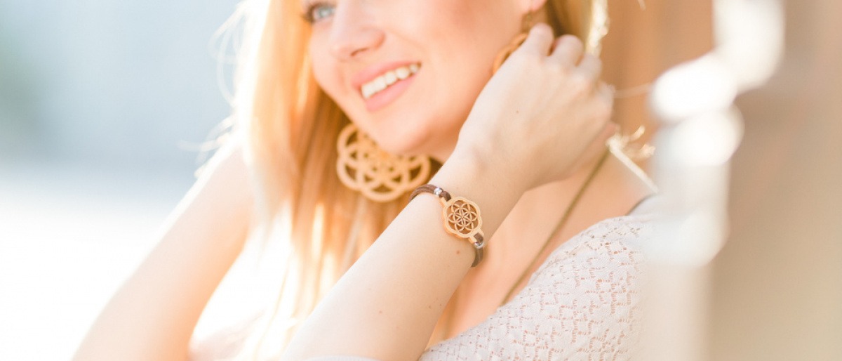 Eine blonde Frau trägt ein Armband und Ohrringe aus Holz