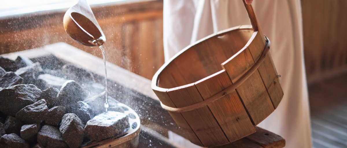 Ein Mann macht einen Aufguss in der Sauna mit ätherischen Ölen