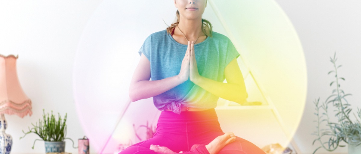Frau im Lotussitz mit Aura in Regenbogenfarben. 