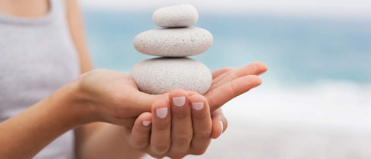 Frau mit Steinturm auf der Hand als Zeichen für Balance und Ayurveda