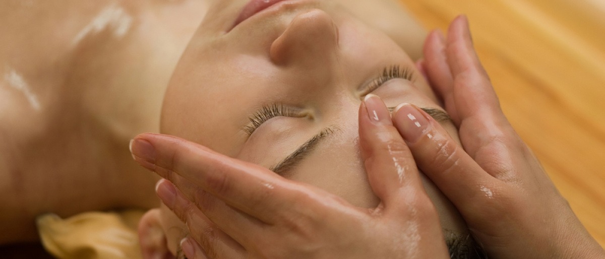 Eine Frau liegt bei einer Ayurveda Kur und erhält eine Ölmassage auf der Stirn