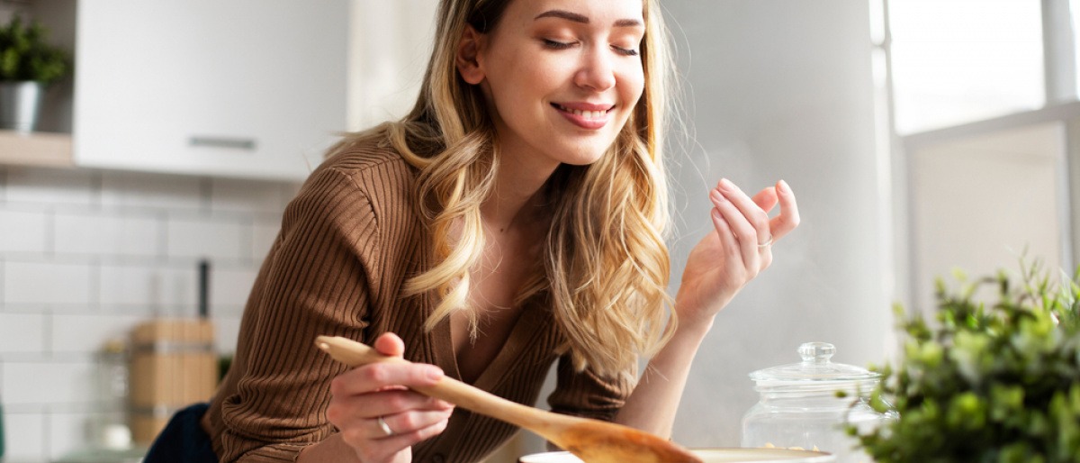 Frau beim Kochen genießt Duft der Speisen
