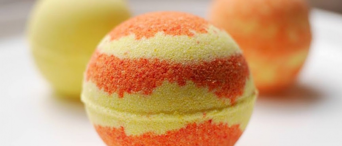 Auf einer weißen Oberfläche liegen orangefarbene Badekugeln