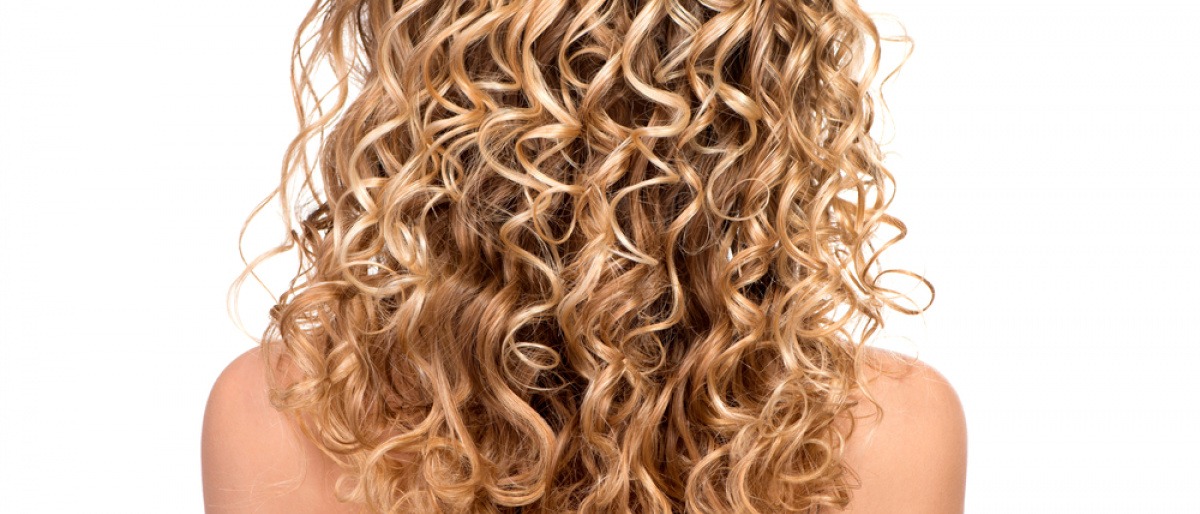 Eine Frau mit Haaren in der Strähnchentechnik Balayage oder Foliyage ist von hinten zu sehen