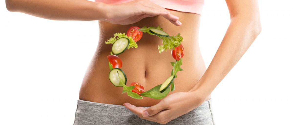 Junge Frau mit einem Kreis aus Gemüse vor dem Bauch