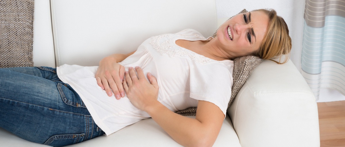Eine Frau mit Darmproblemen im Sommer liegt auf einer Couch