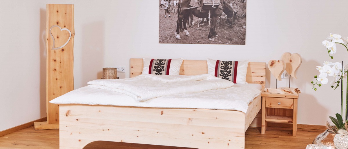 Ein Schlafzimmer mit einem Bett aus Zirbenholz ist aufgeräumt