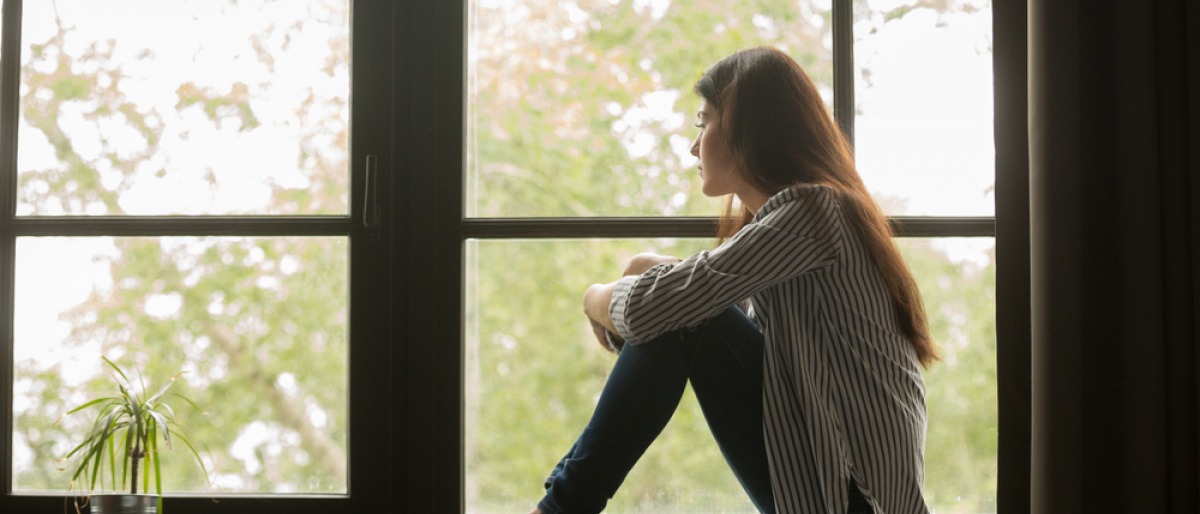 Eine Frau am Fensterbrett, die ihr Bewusstsein verändern möchte